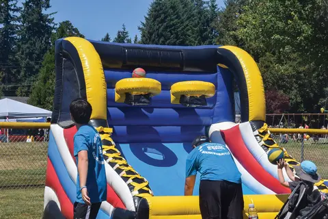 People play a game at an inflatable basketball structure outdoors.
