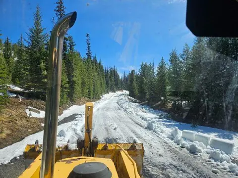 A view from the cab of a vehicle looking down a snowy mountain road.
