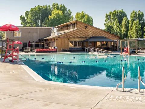 An outdoor swimming pool with a wooden building in the background.