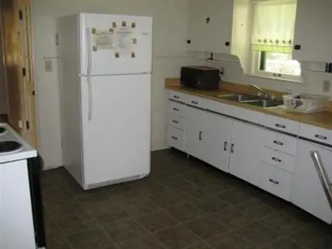 A photo of a kitchen interior featuring white cabinets and a refrigerator.