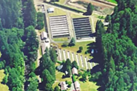 An aerial view shows a facility surrounded by dense trees.