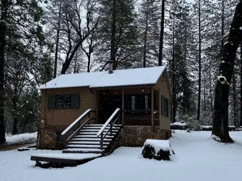 A cabin in the woods covered in snow.