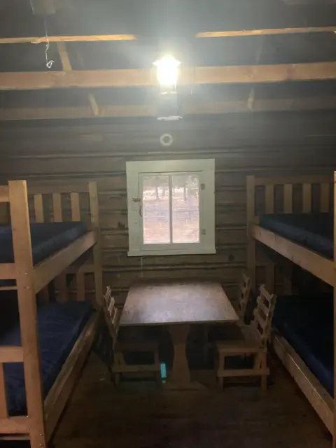 Inside a rustic cabin with bunk beds and a table.