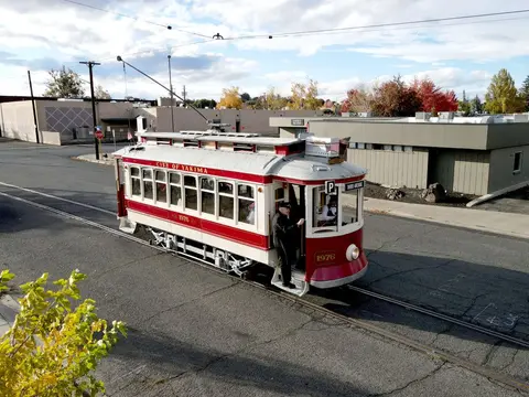 A red and white trolley travels on tracks down a city street.