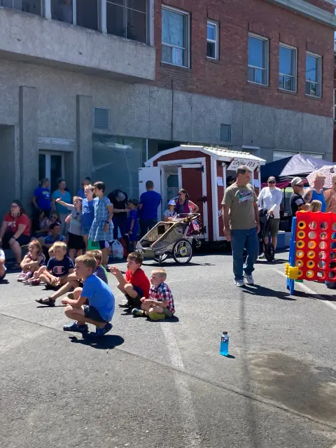 A crowd of children and adults gathered outdoors on a sunny day.