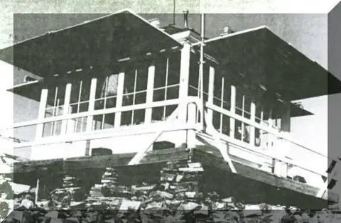 A historic black and white photograph of a fire lookout tower from the outside.