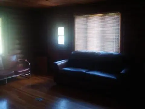 A dark wooden interior room with a sofa and windows.