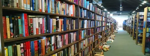 A view looking down an aisle between tall bookshelves inside a large bookstore.