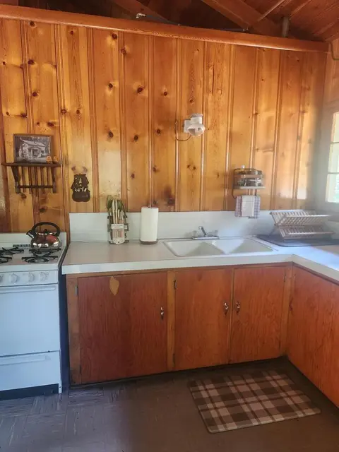 A rustic wooden kitchen with a sink, stove, and cabinets.