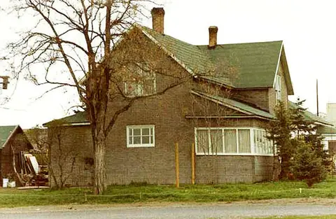 An exterior view of a multi-story brick house with a green roof.