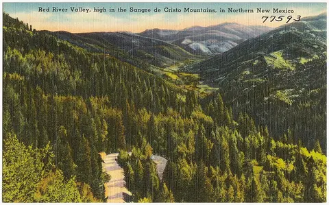 A vintage postcard showing a mountain valley with trees.