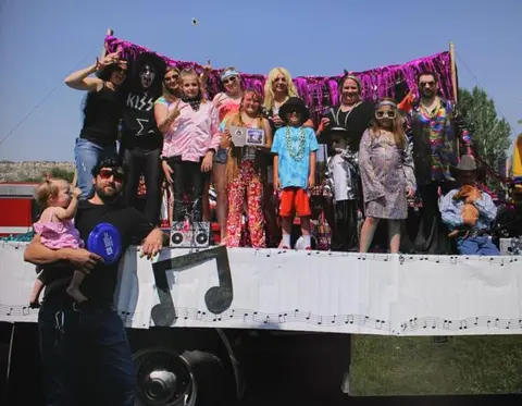 A group of people in costumes pose on a float during a parade.