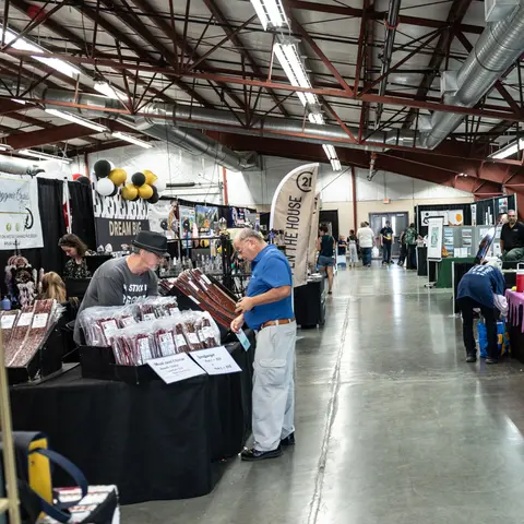 People walking through a large indoor market or trade show.