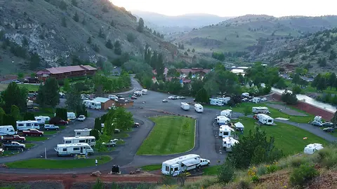 A high-angle view shows an RV park nestled in a valley with hills and a river.