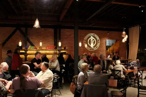 An interior view of a crowded restaurant or bar with brick walls and patrons sitting at tables.