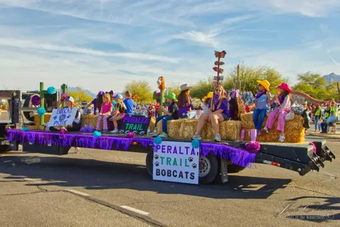 Children sit on hay bales decorating a parade float.
