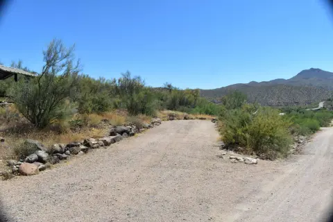 A dirt road cuts through a desert landscape under a clear blue sky.
