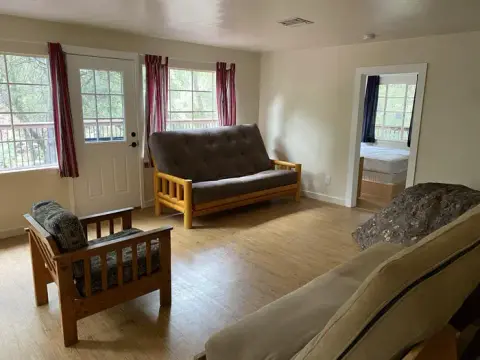 An interior shot of a furnished living room with wooden floors and a couch.