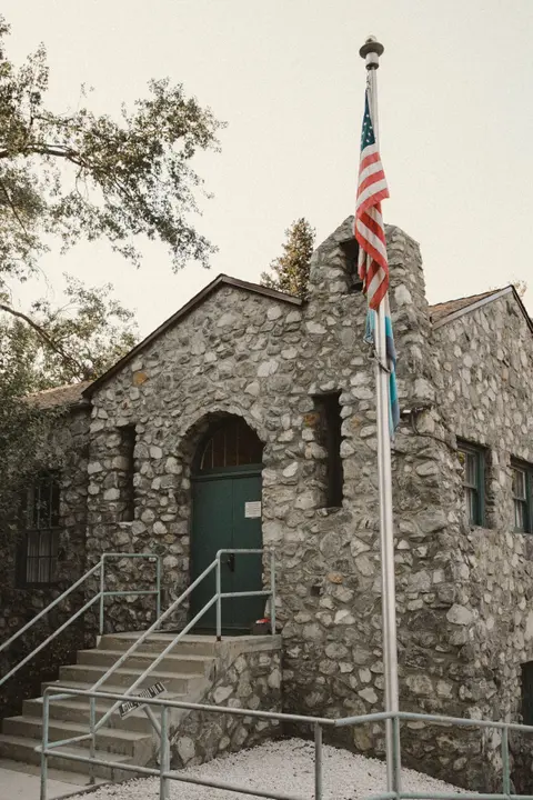 A stone building with a flagpole flying an American flag in front.