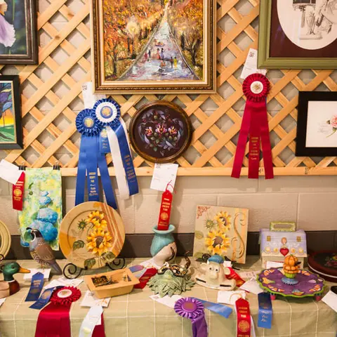 A collection of art pieces and ribbons displayed on a lattice wall and table.