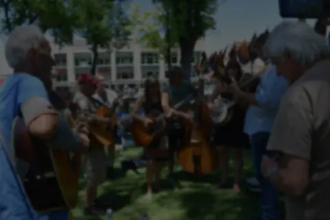 A group of musicians playing acoustic instruments outdoors.