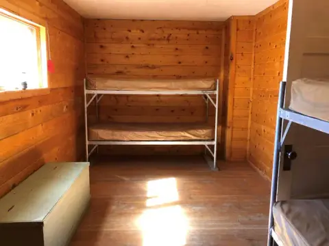 A rustic wooden room with bunk beds and a chest.