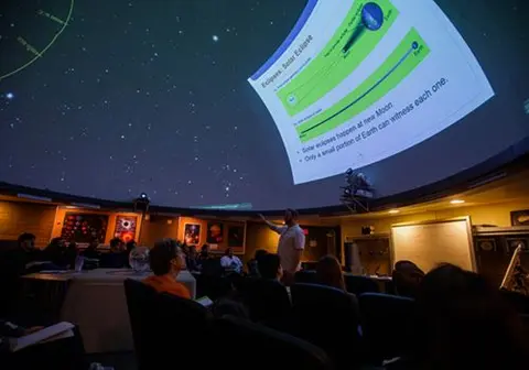 A planetarium presentation about solar eclipses is projected onto the dome above an audience.