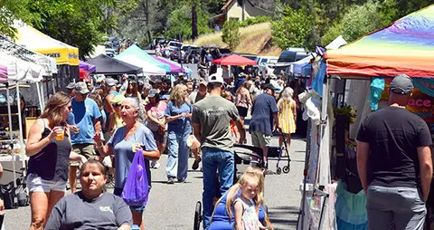 A busy outdoor street market with many vendors and shoppers.