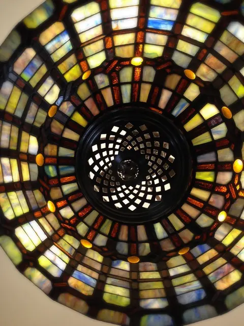 A close-up view looking up at a circular stained glass ceiling lamp.