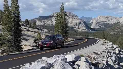 A red SUV drives along a winding mountain road.