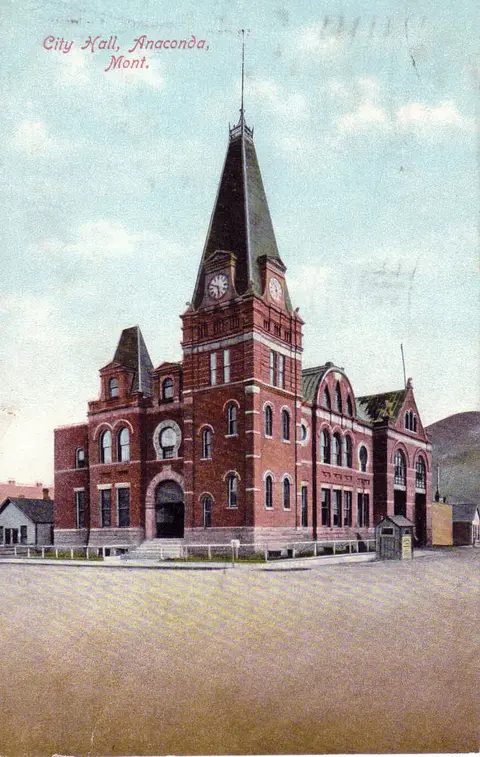 A historic postcard showing a brick building with a tall clock tower.