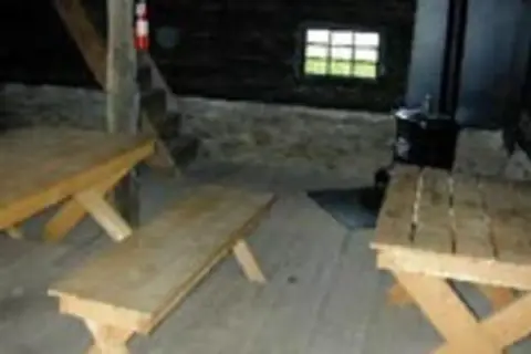 Interior of a rustic building with wooden tables and benches.