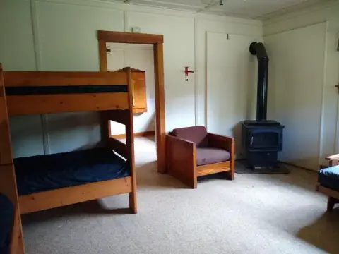 An interior view of a cabin with a wooden bunk bed and a stove.