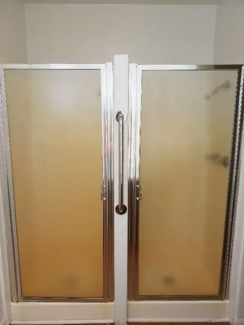 A photo of shower stalls with frosted glass doors.