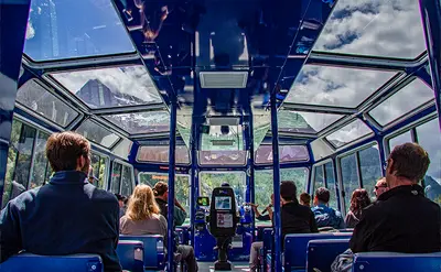 Passengers are seated inside a tour vehicle with large glass roof panels.