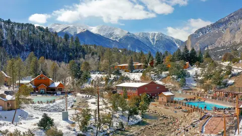 A resort with pools and buildings nestled in a snowy mountainous landscape.