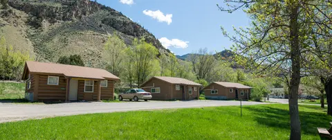 A row of small log cabins situated at the base of a mountain.
