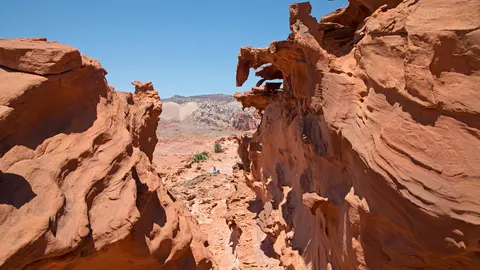 A view through red sandstone rock formations toward a distant mountain range.