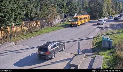 A high-angle view shows a road with multiple vehicles, including a school bus and an SUV.