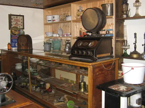 An interior view of a historic shop with a glass display counter and vintage items.