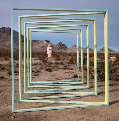 A series of colored rectangular frames stand in a desert landscape.