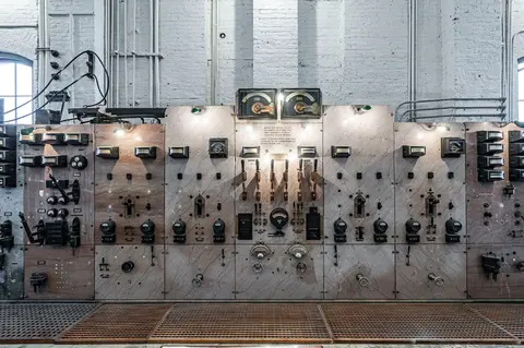 An old control panel featuring numerous gauges and switches mounted on a marble surface.