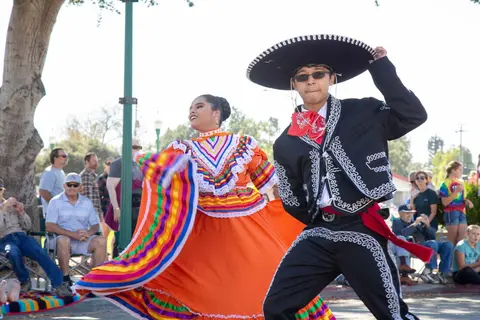 A young man and woman perform a traditional dance outdoors.