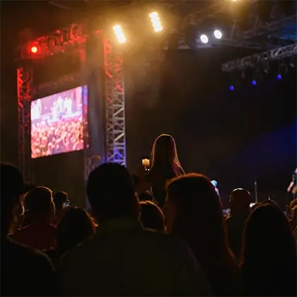 A crowd of people watch a concert at night under bright stage lights.