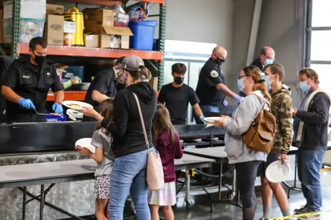 People wait in line to receive food served inside a building.