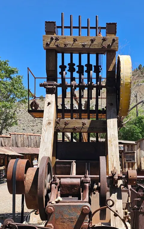 A photograph of an antique outdoor stamp mill structure.