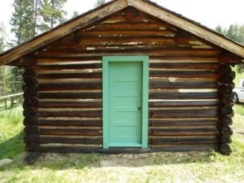 A small log cabin with a green door.