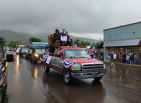 A truck in a parade carrying people on a couch.