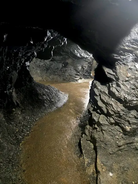 A narrow water channel runs through a dark underground cave.
