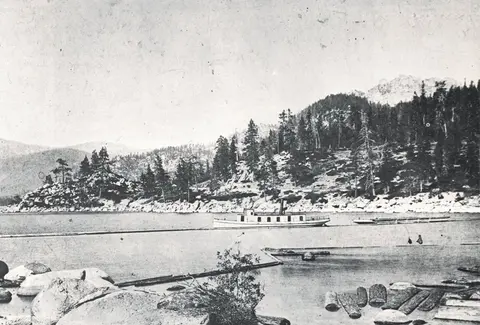 An old photograph shows a steamboat on a lake near a heavily forested shore.